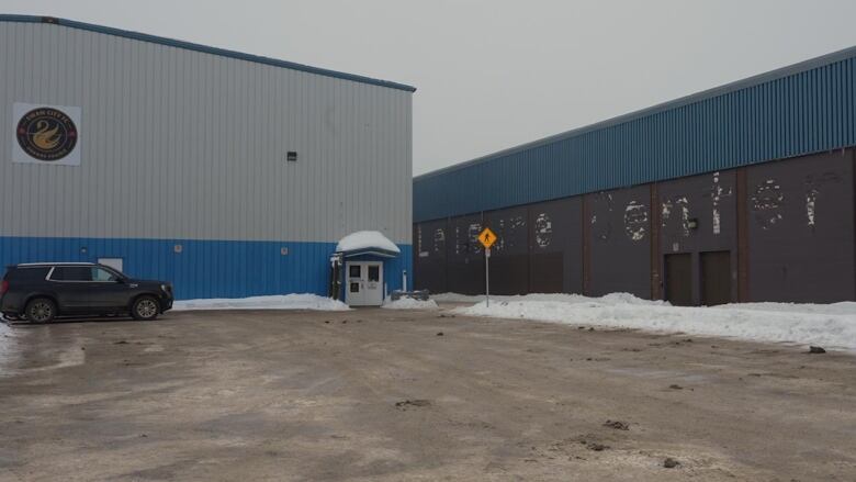 Two grey buildings on a winter day. The one on the right has a faded sign that says Leisure Centre.