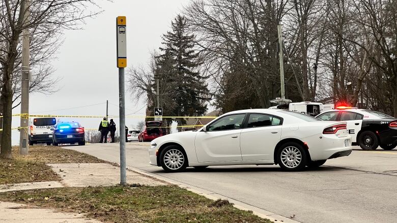 Police tape and police cars on a road. 