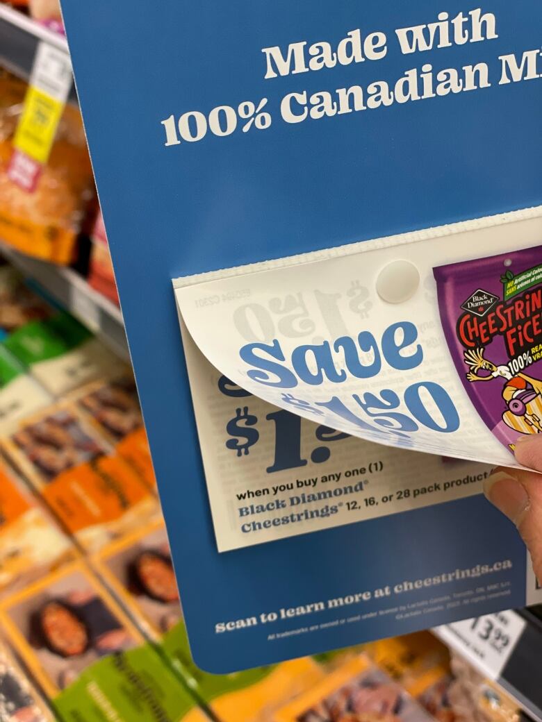 A coupon titled 'Save $1.50' is being torn off a pad at a supermarket.