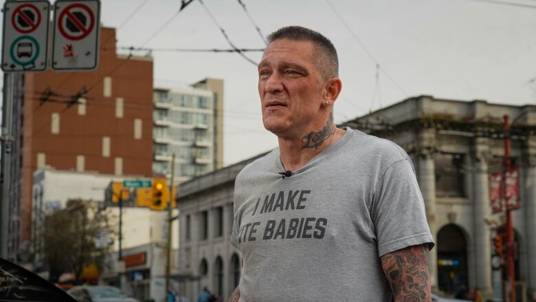 Jerry Martin wears a grey shirt and looks away from the camera. He has short grey hair and tattoos on his arm and neck.