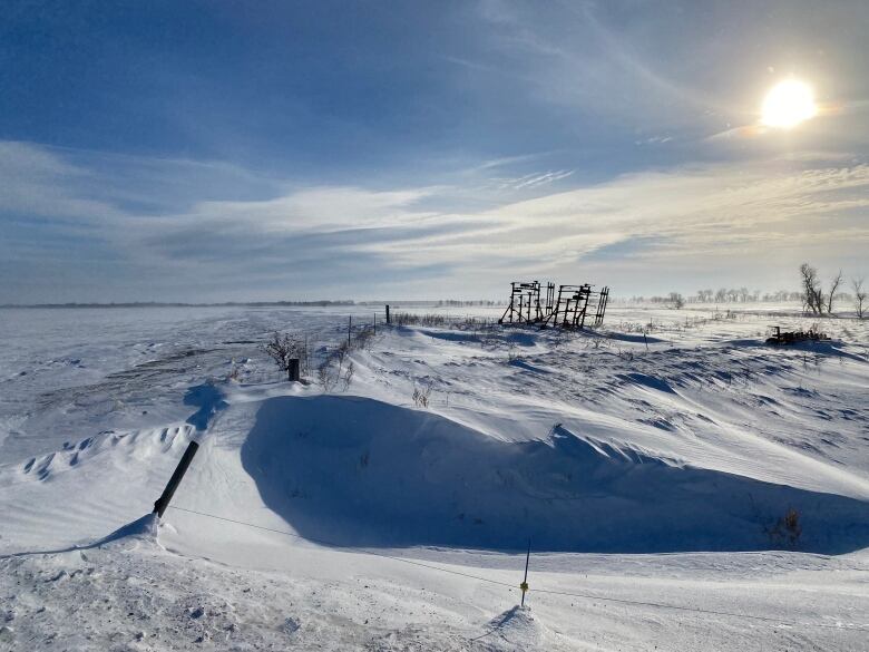 A field covered in snow drifts on a sunny winter day.