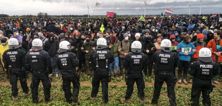 A line of police face off with a crowd of protesters.