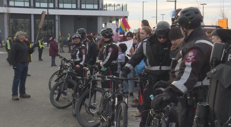 A row of police officers, some with bikes, stand between protestors and counter-protestors