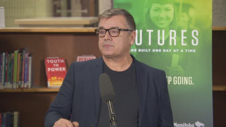 A man stands by a podium with a green sign behind him.