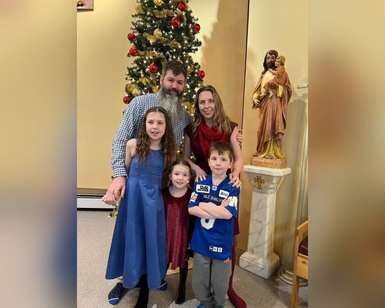 A man and a woman stand with three children near a Jesus Christ statue.