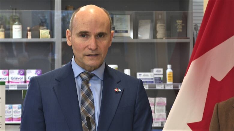 Jean-Ives Duclos standing in front of pharmacy shelves.