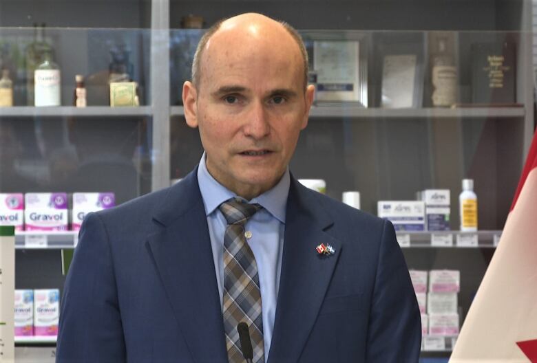 Jean-Ives Duclos standing in front of pharmacy shelves.