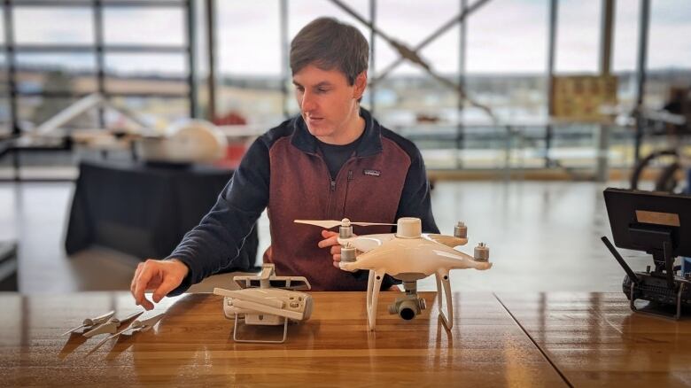 A man looks at a drone on the table in front of him 