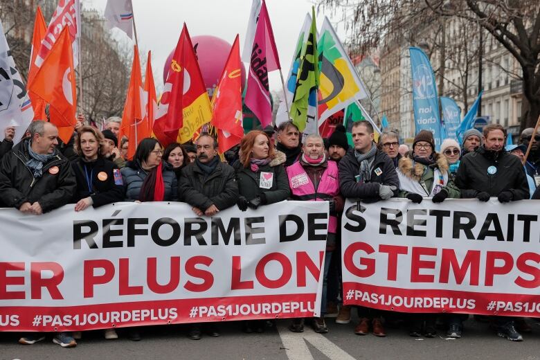 People stand with banners and flags during a union demonstration.