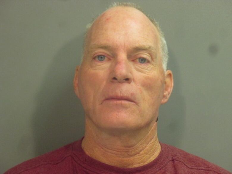 Close-up of grey haired man in dark red tee shirt.