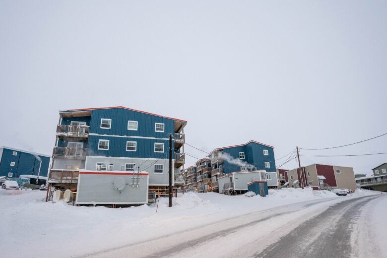 Large apartment buildings on stilts next to a road.