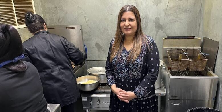 A woman stands in a kitchen.