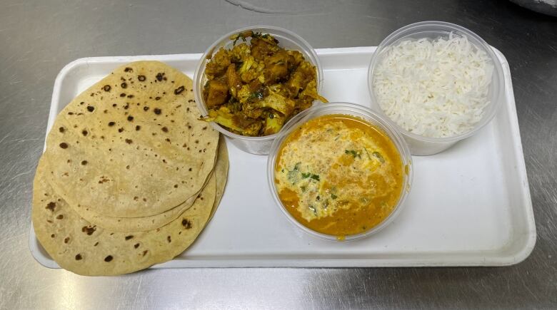 Containers of food with roti.