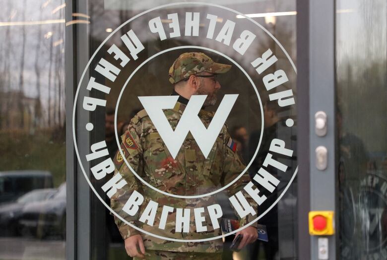 A person in military garb leaves a building.