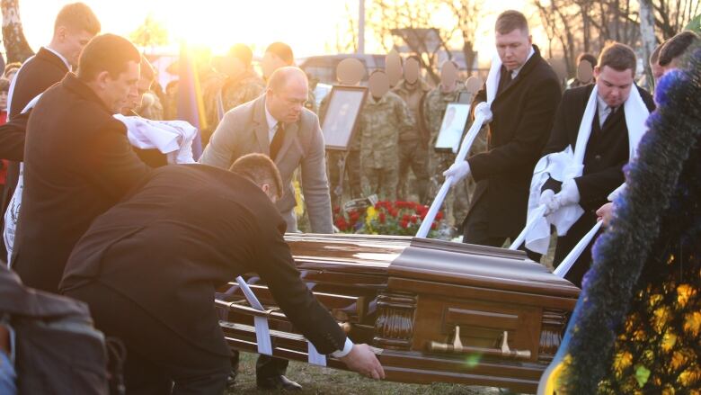 A group of men lower Grygorii Tsekhmistrenko's coffin into a grave at a cemetery located in a southern suburb of Kyiv, Ukraine.