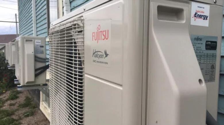 A series of electric heat pumps installed on the back of a building.