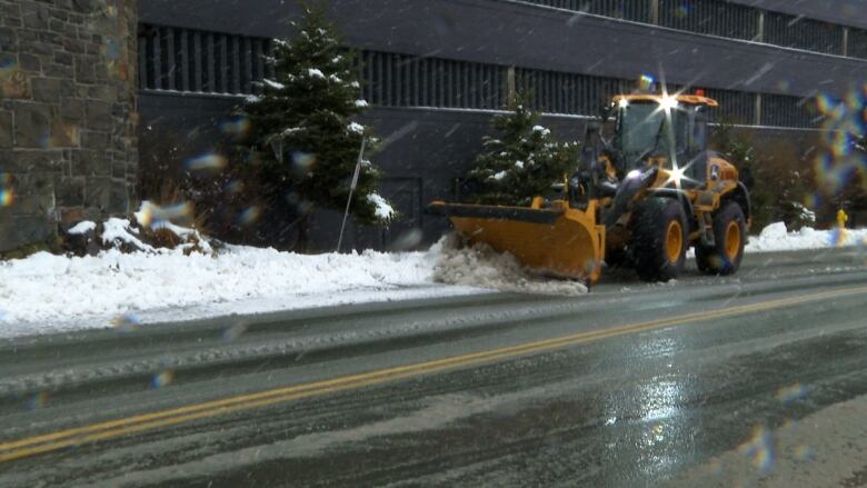 A snow plow drives down a street.