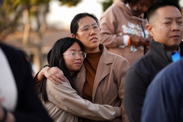 Two persons embrace in an outdoor setting.