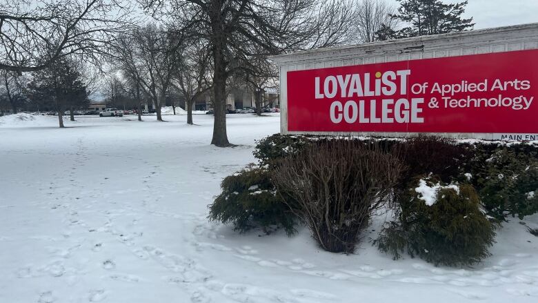 A sign reading 'Loyalist College of Applied Arts and Technology' sits atop a snowy field.