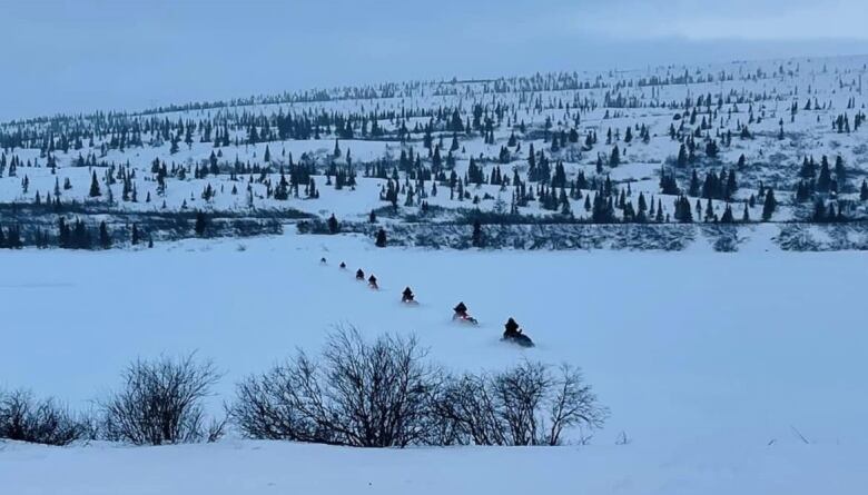 A line of snowmobiles travel away from Kawawachikamach in northern Quebec in the pre-dawn of January 13.