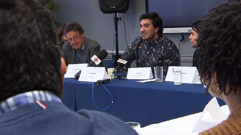 People sitting around table with microphones