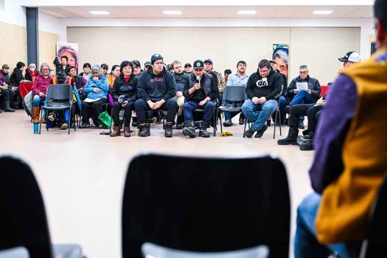 A row of people in chairs in a small community gym. 