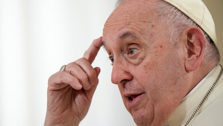 Pope Francis, in a white robe, is pictured in a close-up.