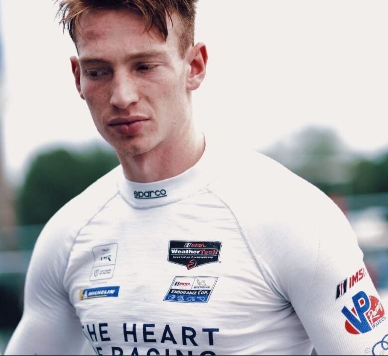 A racing driver with the top half of his race suit off