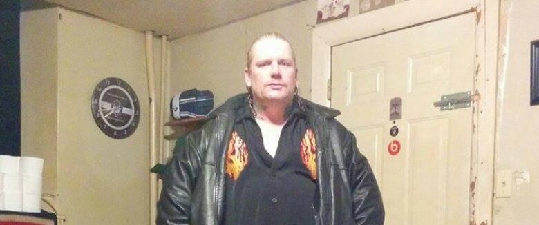 Man in black leather jacket standing with his hands on his hips