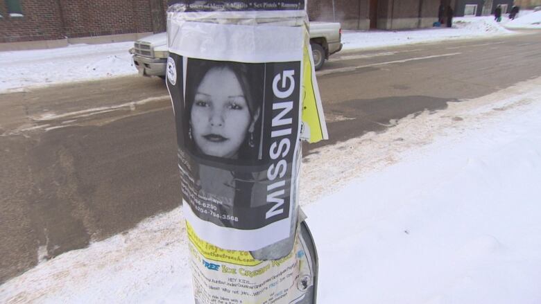 A missing poster of a woman named Ashlee Shingoose is taped on a pole on a wintery day.