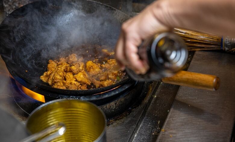 Chili chicken being cooked in a wok.