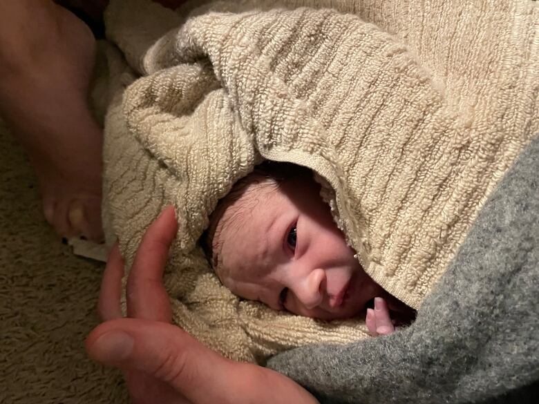 A newborn is wrapped up in a towel.