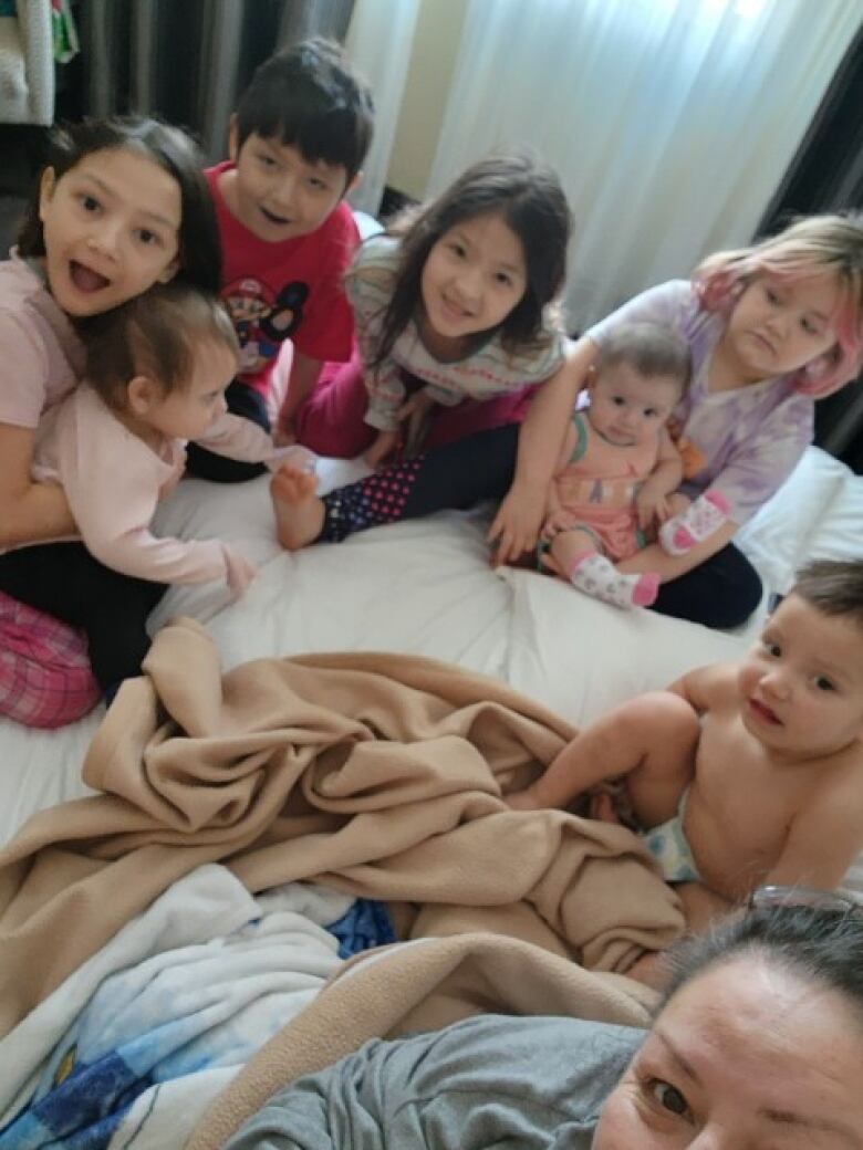 Eight people, including seven young children, on one bed in a hotel room. 