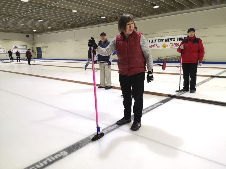 A woman is pictured holding a broom with a light on it on the ice.