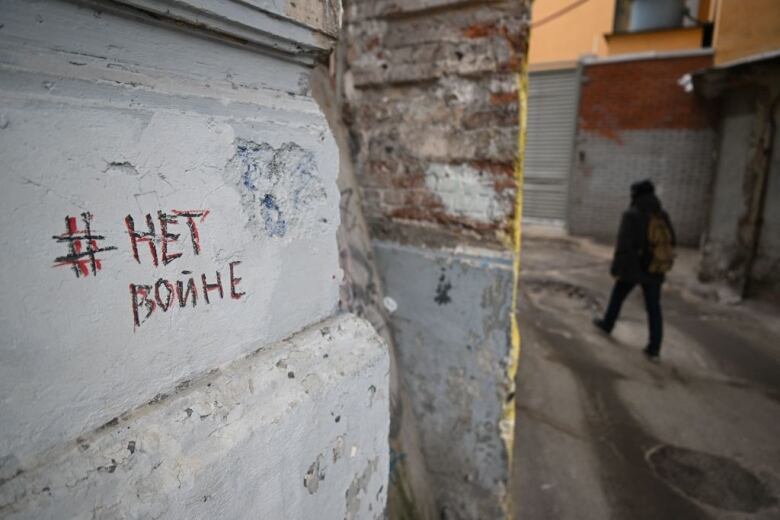 A man walks past graffiti on a wall in Moscow that reads 