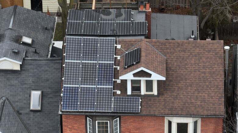 An aerial view of several solar panels on the roof of a home.