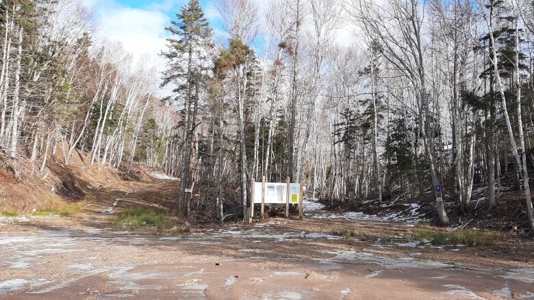 The entrance to this rural trail system has no snow on the ground, grass is visible.