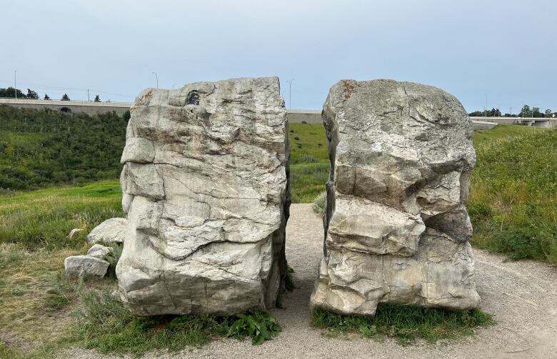 A large rock split in half sits in a park.