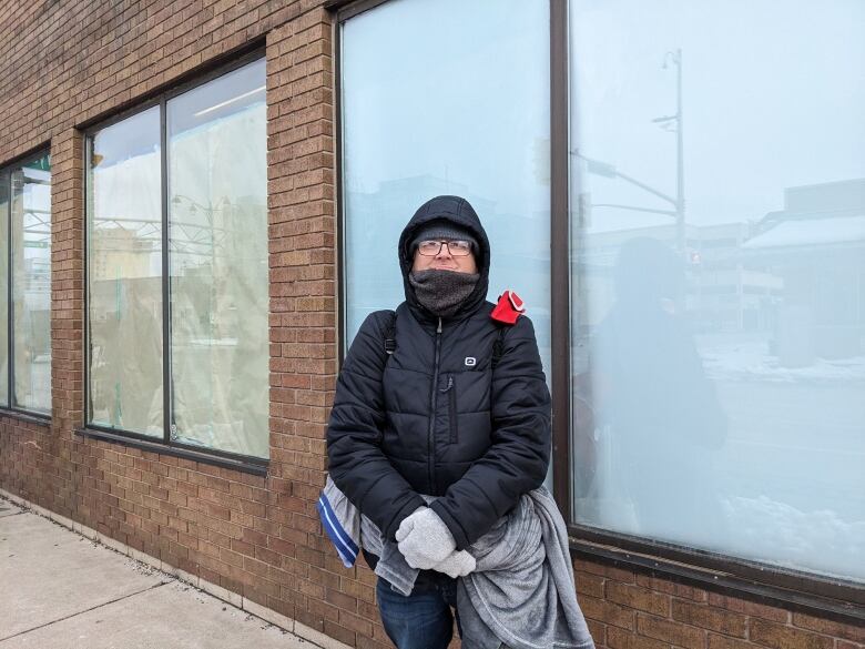 A man standing against a building.