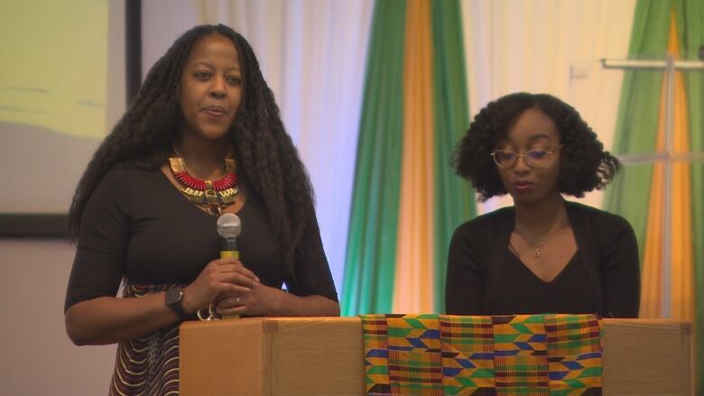 Two women stand at the church lectern, before starting to sing.