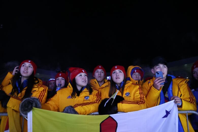 Athletes holding a banner at the MacDonald Island Park in Fort McMurray, Alta., for the Arctic Winter Games Opening Ceremonies.