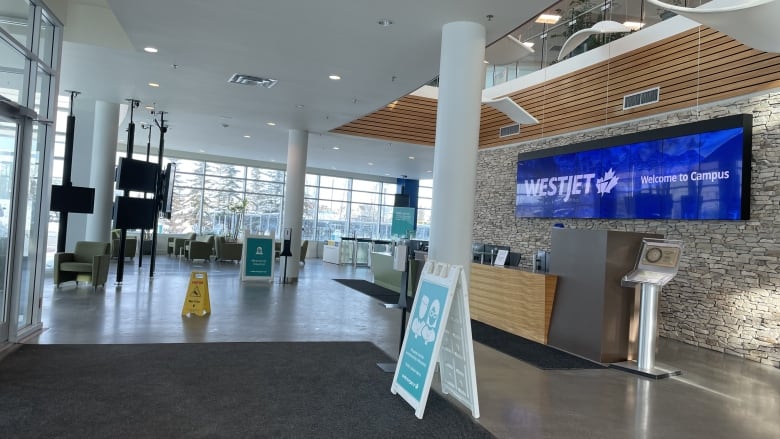 A wide shot of WestJet headquarters, with a big blue sign behind a desk saying 