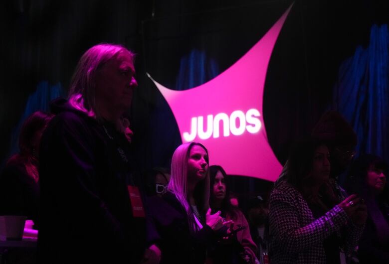 People gather under dim neon pink lighting.