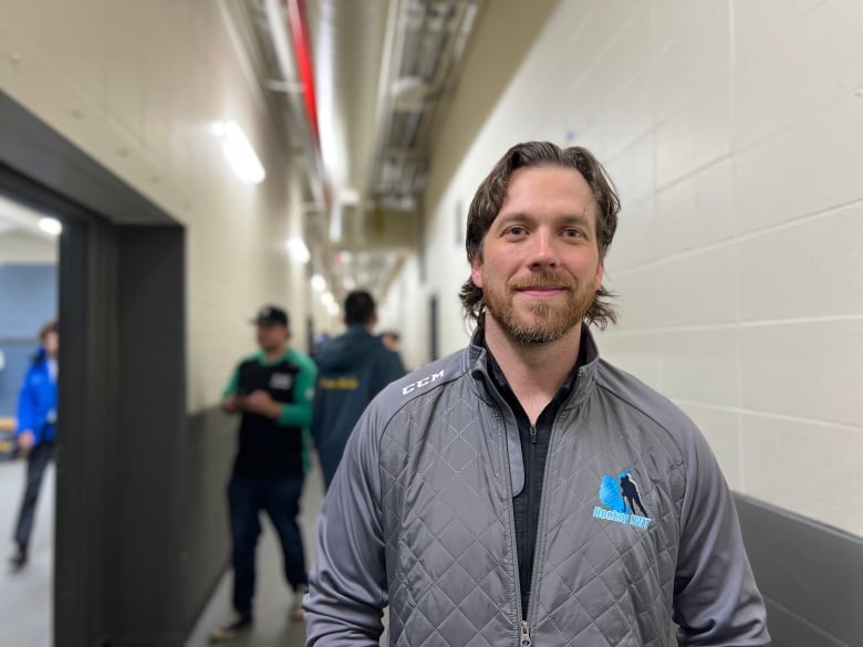 A man stands smiling in a sports facility. 