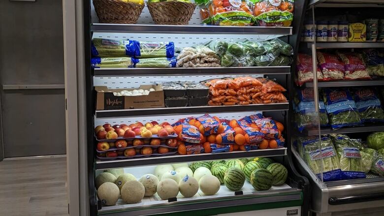 A standup cooler containing fresh fruits and vegetables is shown.