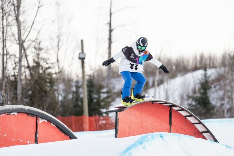 A snowboarder slides along a rail during a competition event.