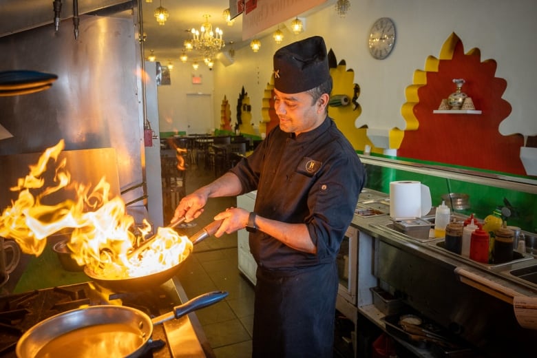 Cooking the momos in a wok to coat them in a sauce