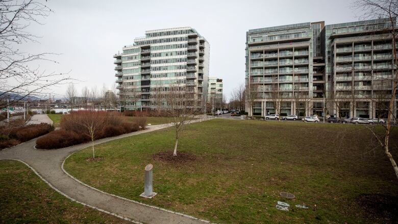 An open grassy area ringed by a cobbled pathway is shown bordered by three highrises.