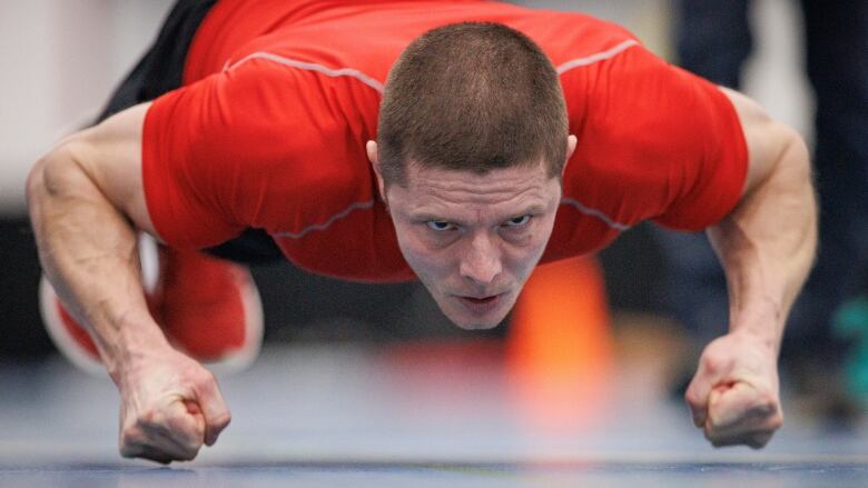 A man focuses intensely on what he's doing as he knuckle-hops across the floor.