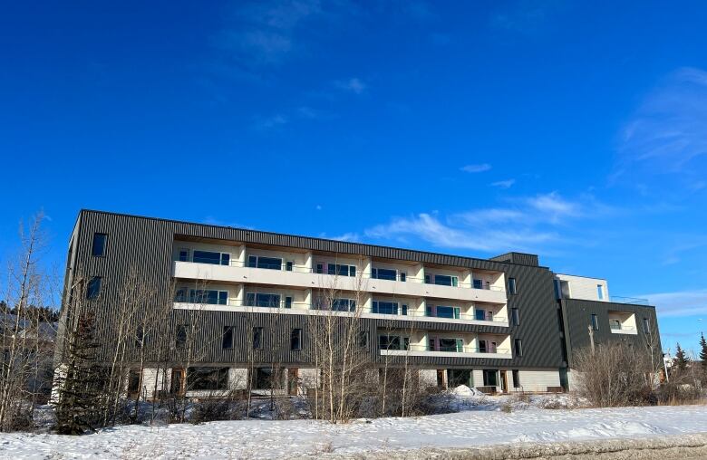 A large apartment complex is seen against a blue sky.